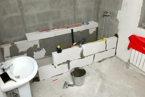 interior do uma Novo banheiro com a concreto blocos e construção ferramentas. foto