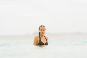 retrato bela jovem asiática usar biquíni ao redor da piscina em hotel resort perto do mar oceano praia foto