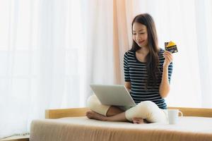 retrato bela jovem asiática usando computador notebook ou laptop com cartão de crédito para fazer compras foto