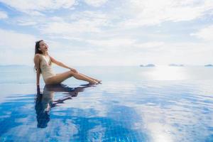 retrato jovem mulher asiática relaxar sorrir feliz ao redor da piscina no hotel e resort foto