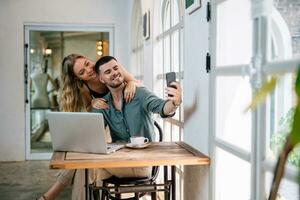 feliz casal levando selfie através inteligente telefone às lar. pessoas e moderno tecnologia conceito. foto