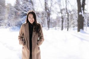 retrato jovem linda mulher asiática sorrir feliz viajar e desfrutar com neve inverno temporada foto