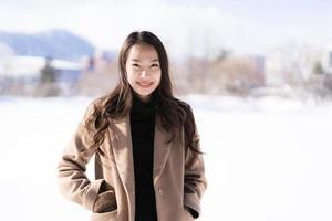 retrato jovem linda mulher asiática sorrir feliz viajar e desfrutar com neve inverno temporada foto