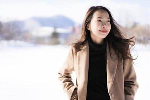 retrato jovem linda mulher asiática sorrir feliz viajar e desfrutar com neve inverno temporada foto