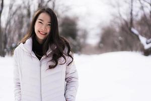 bela jovem asiática sorrindo feliz por viajar na neve, inverno foto