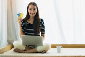 retrato bela jovem asiática usando computador notebook ou laptop com cartão de crédito para fazer compras foto