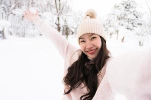 retrato jovem linda mulher asiática sorrir feliz viajar e desfrutar com neve inverno temporada foto