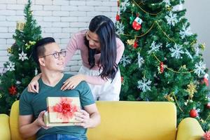 jovem casal asiático está dando um presente de Natal. o conceito de uma vida feliz no natal foto