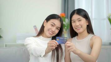 dois ásia sorridente mulheres dentro mostrando crédito cartão. conectados sucesso Comprar oferta. foto