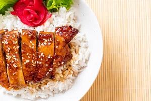Frango grelhado com molho teriyaki na tigela de arroz com cobertura foto