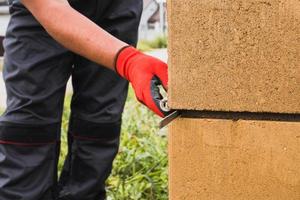 adesivo à base de cimento para bloco de pedra de alvenaria e tijolo em construção - um pedreiro profissional no trabalho foto