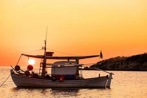 paisagem com barco de pesca no mar com lindo nascer do sol no fundo foto