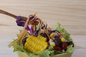 deliciosa salada de vegetais frescos com um garfo de madeira foto