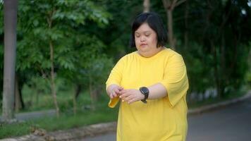 ásia mulher com baixa síndrome caminhando para exercício dentro a parque. foto
