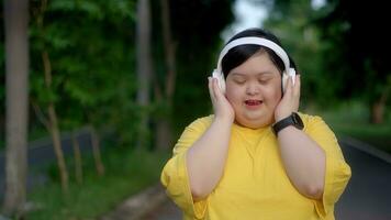 baixa síndrome menina exercício dentro a parque vestindo fones de ouvido. foto