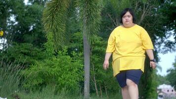 ásia mulher com baixa síndrome caminhando para exercício dentro a parque. foto
