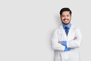 retrato de médico masculino sorrindo com estetoscópio e cruz de braço isolado no fundo branco. conceito de seguro saúde. foto