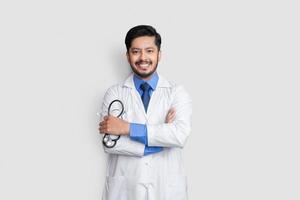 jovem médico masculino cruza os braços sobre fundo isolado sorrindo foto