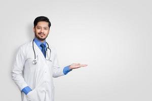 médico vestindo uniforme sorrindo enquanto apresenta e aponta isolado no fundo branco com espaço de cópia foto