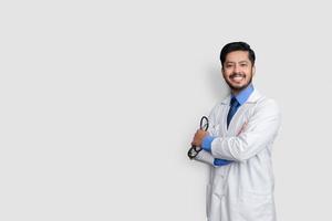 jovem médico masculino cruza os braços sobre fundo isolado rindo foto