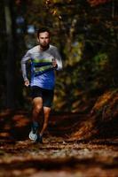 atleta correndo durante os trens de preparação para a maratona na floresta de outono foto