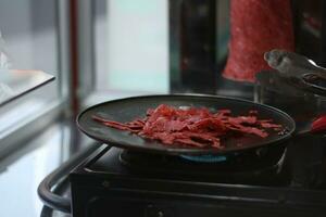 uma beira da estrada vendedor é fritar fatias do carne Como a a Principal ingrediente para fazer kebabs. foto