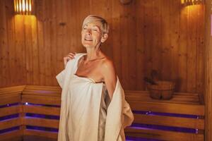 maduro mulher é relaxante dentro sauna. saudável estilo de vida para idosos pessoas. spa conceito. foto