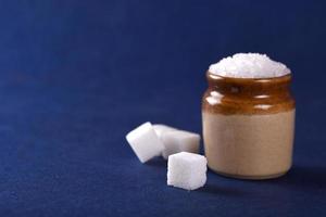 açúcar. açúcar granulado branco e açúcar refinado em um fundo azul