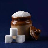 açúcar. açúcar granulado branco e açúcar refinado em um fundo azul