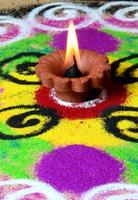 lâmpadas diya de argila acesas durante a celebração do diwali, rangoli ao fundo
