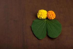 festival indiano dussehra, mostrando folhas douradas e flores de calêndula em um fundo marrom. foto