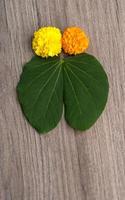 festival indiano dussehra, mostrando folhas douradas bauhinia racemosa e flores de calêndula em um fundo de madeira. foto