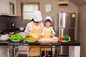 mulher asiática com filho cozinhando comida na cozinha de casa foto