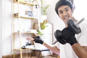 homem asiático caucasiano segurando halteres em casa foto