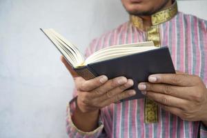 Mão de homem muçulmano lendo livro sagrado Alcorão com espaço de cópia foto