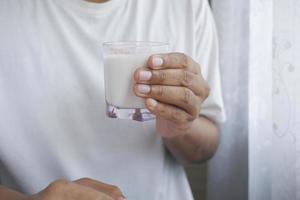 mão do homem segurando um copo de leite no início da manhã foto