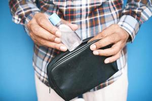 mão de homem colocando desinfetante para mãos em uma pequena bolsa foto