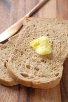 fatia de manteiga e pão integral na tábua de cortar