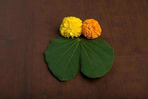 festival indiano dussehra, mostrando folhas douradas bauhinia racemosa e flores de calêndula em um fundo marrom. foto