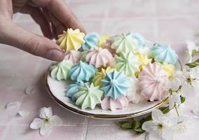 pequenos merengues coloridos no prato de cerâmica foto