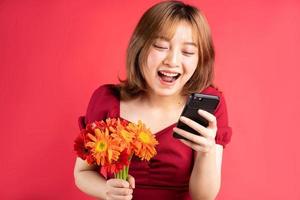 jovem segurando flores e usando o telefone com uma expressão alegre no fundo