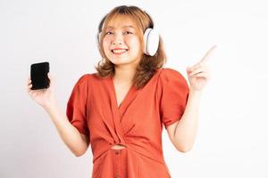 jovem asiática usando seu telefone e usando fones de ouvido para curtir música foto