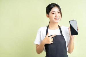 Garçonete asiática segurando o telefone com uma cara alegre