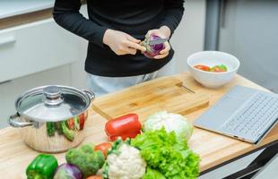 mulher está aprendendo a cozinhar sozinha em casa, curso de culinária online foto