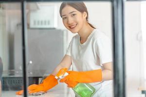 linda mulher asiática limpando a área da cozinha foto