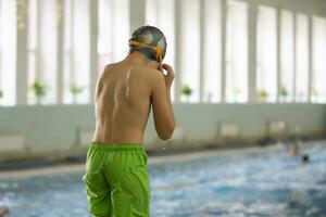 uma Garoto dentro uma natação boné e óculos mergulhos para dentro uma Esportes piscina. foto