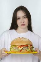 uma mulher é segurando uma grande churrasco Hamburger sanduíche em a fundo. velozes Comida conceito. a menina tem uma enorme Hamburger. foto