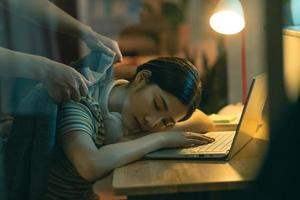 a mulher asiática está adormecendo enquanto trabalhava à noite, o marido estava cobrindo a esposa adormecida foto