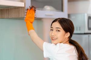 linda mulher asiática limpando armários de cozinha foto