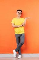 foto de corpo inteiro de homem asiático em camisa amarela em fundo laranja